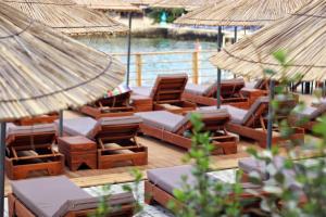 una terrazza con sedie, tavoli e ombrelloni di Golden Beach Suites a Sarandë