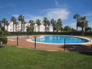 a swimming pool in a park with palm trees at Reina Sofía Apartment in Costa Ballena