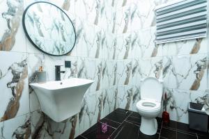 a bathroom with a sink and a toilet and a mirror at MODERN 2-BeDROOMS in Accra +6 photos