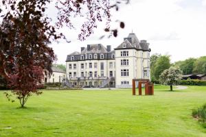 a large white building with a grassy field in front of it at Hébergement au château 105 in Tinlot +11 photos