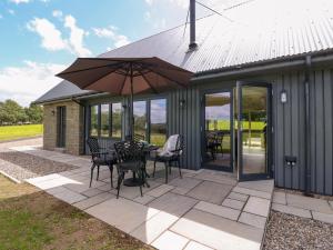a patio with a table and chairs and an umbrella at Strawberry Cottage in Blairgowrie