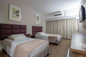 a hotel room with two beds and a television at Hotel Victoria Villa Curitiba by Nacional Inn in Curitiba