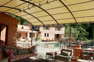 un patio esterno con divano e sedie accanto alla piscina di Propriété Fontaine Margo a Seillans