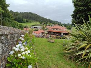 a stone wall with flowers in front of a house at Casa Labrega da Torre in Silleda