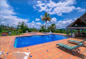 a swimming pool with two chairs and a gazebo at Finca Hotel El Ocaso in Quimbaya