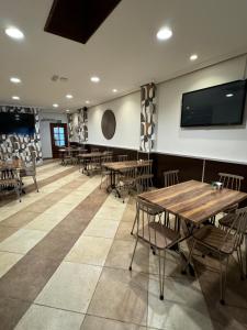 a dining room with tables and chairs and a flat screen tv at Hotel Anunciada in Baiona