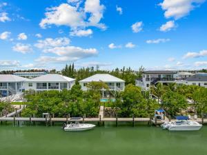a dock with boats in the water in front of houses at Emerald Oasis Deluxe Waterfront Gem, Heated Pool with Dock in Marathon