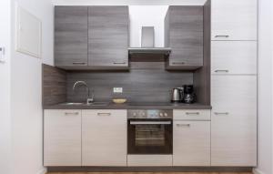 La cuisine est équipée de placards blancs, d'un évier et d'un four. dans l'établissement Nice Apartment In Malinska With Wifi, à Malinska