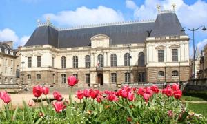 a large building with red tulips in front of it at Gîte LA Maison LA in Saint-Aubin-dʼAubigné