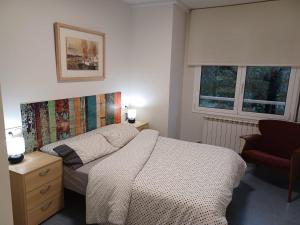 ein Schlafzimmer mit einem Bett, einem Stuhl und zwei Fenstern in der Unterkunft Apartament Especial Vic in Vic