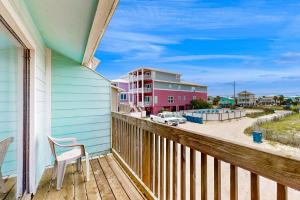 a balcony with a white chair and a pink building at The Breeze in Gulf Shores