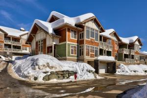 a snow covered apartment building with a pile of snow at Settler's Crossing #56 ski-in ski-out condo with private hot tub in Sun Peaks
