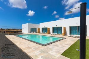 a swimming pool in front of a white building at Lola Loft Lajares iRent Fuerteventura in La Oliva