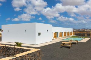 Un edificio blanco con una mesa de picnic y una piscina. en Lola Loft 2 Lajares iRent Fuerteventura, en La Oliva