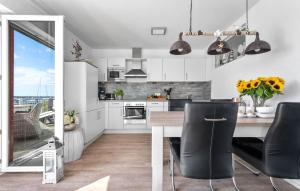 a kitchen with white cabinets and a table with chairs at Am Yachthafen in Olpenitz