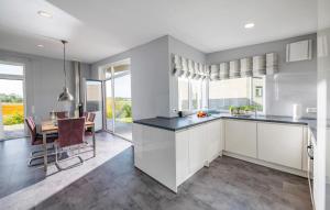 a kitchen with white cabinets and a dining room with a table at Auszeit in Gelting