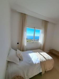 une chambre avec un lit blanc et une fenêtre dans l'établissement Tanger, Vue Mer Panoramique, à Noûnouech