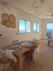 - une table en bois dans une chambre avec des chaises et des fenêtres dans l'établissement Tanger, Vue Mer Panoramique, à Noûnouech
