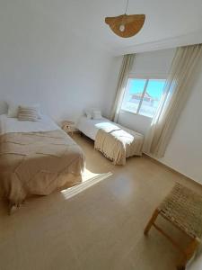 Cette chambre blanche dispose de deux lits et d'une fenêtre. dans l'établissement Tanger, Vue Mer Panoramique, à Noûnouech