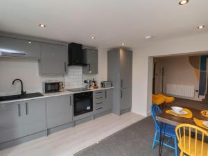 a kitchen with gray cabinets and a table with chairs at Apt 1 Hunter's Quay in Bridlington