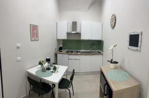 Una cocina con gabinetes blancos y una mesa y sillas. en NINAS HOME AiRPORT, en Catania