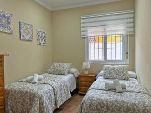 a bedroom with two beds and a window at Villa Victoria - Ole Solutions in El Puerto de Santa María