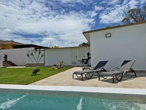 a patio with two chairs and a swimming pool at Villa Victoria - Ole Solutions in El Puerto de Santa María