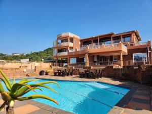 a house with a swimming pool in front of a building at Golden Dawn Chalets in La Mercy