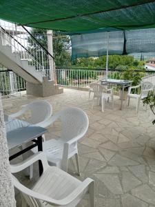 a group of white chairs and tables on a patio at Maria Apartments in Asíni