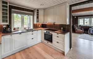 a kitchen with white cabinets and wooden floors at 3 Bedroom Lovely Home In Skollenborg in Lindåskroken