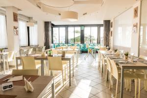 a restaurant with tables and chairs and windows at Hotel Rudy Cervia in Cervia