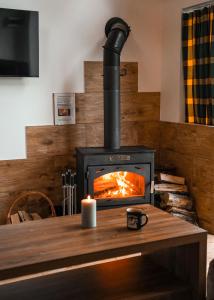 a wood fired stove with a candle on a table at Domki pod Bukowym Lasem in Wańkowa