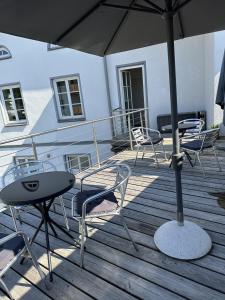a deck with chairs and tables and an umbrella at meywohnen Stadthaus Bad Aibling in Bad Aibling