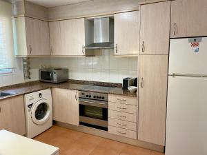 eine Küche mit einem weißen Kühlschrank und einem Geschirrspüler in der Unterkunft Agradable adosado con piscina y jardín in Canet d'en Berenguer