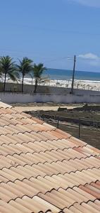 a roof on a beach with palm trees and the ocean at Casa Mar in Praia Da Caueira