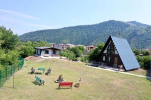 a house with a yard with chairs and a building at Borjomi Cottage Sadgeri in Sadgeri
