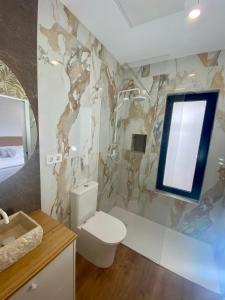 a bathroom with a toilet and a marble wall at La Santillana Luxury Apartments in Santillana del Mar