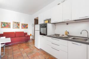 eine Küche mit weißen Schränken und einem roten Sofa in der Unterkunft Corso 264 in Pesaro + 8 Fotos