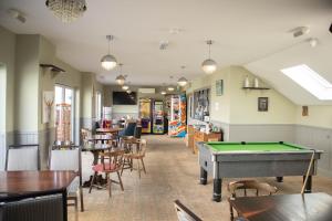 a room with a pool table and tables and chairs at 23 Chestnut Grove in Kirkcolm