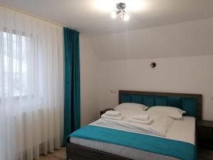 a bedroom with a bed with blue curtains and a window at Casa Vânătorilor in Arieşeni +14 photos