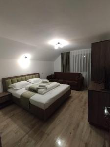 a bedroom with a large bed and a couch at Casa Vânătorilor in Arieşeni