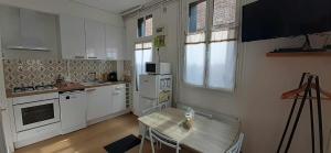 a kitchen with white appliances and a wooden table at L'Escapade Tréportaise in Le Tréport