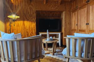 Una sala de estar con dos sillas y un televisor. en Departamento completo en San Carlos de Bariloche, Argentina, en San Carlos de Bariloche