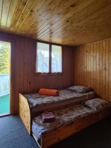 a room with two beds in a wooden cabin at Andrea Vendégház in Izvoru Mureşului