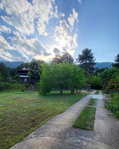 a path in a park with trees and a house at Koti Mountain House in Litochoro