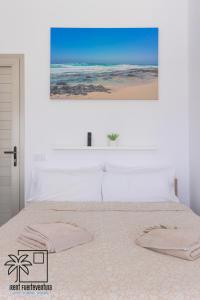Un dormitorio con una cama con un cuadro en la pared. en Lola Loft 4 Lajares iRent Fuerteventura, en La Oliva