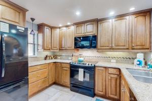 una cucina con armadietti in legno ed elettrodomestici neri di Patio Condo in Oceanfront Community w/ Pool – Walk to Beach a St. Augustine
