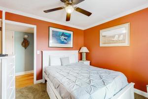 una camera da letto con pareti arancioni e un letto con ventilatore a soffitto di Patio Condo in Oceanfront Community w/ Pool – Walk to Beach a St. Augustine Altre 26 foto