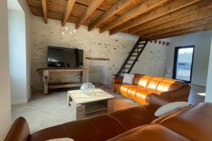 a living room with a leather couch and a tv at Le Loft des Lumières in Château-Gontier
