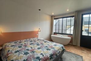 a bedroom with a bed and a tub and a window at Le Loft des Lumières in Château-Gontier